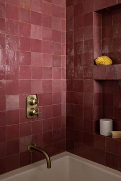 a bathroom with pink tiled walls and gold faucet in the shower stall area