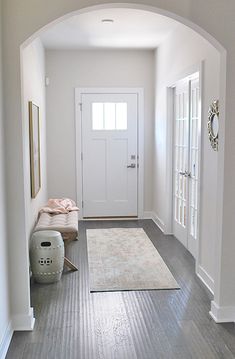 an archway leading to a bedroom with a white door and rug on the floor in front of it