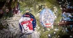 two ornaments hanging from a christmas tree in the shape of an ornament with a snowman on it