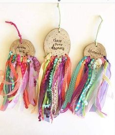 three wooden tags with different colored ribbons hanging from the strings on a white wall, one says choose your dream