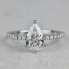 a pear shaped diamond engagement ring with pave set shoulders