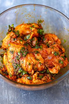 a close up of a bowl of food with meat and herbs in it on a table