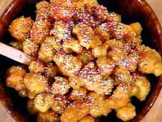 a wooden bowl filled with pasta covered in sprinkles