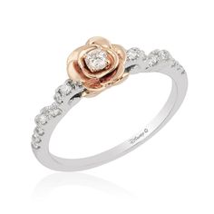 a white and gold ring with a rose on the center, surrounded by small diamonds