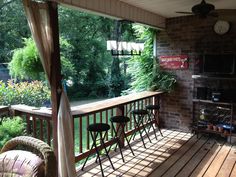 a porch with chairs and a tv on the wall next to a grilling area