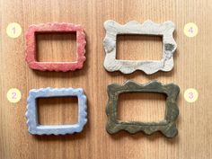 four different colored frames sitting on top of a wooden table