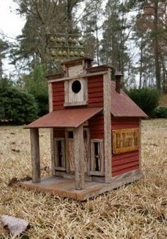 a small red bird house sitting on top of dry grass