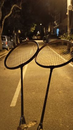 two tennis racquets sitting on top of each other in front of a street