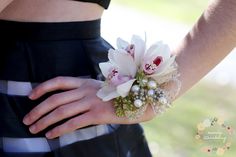 a close up of a person's hand wearing a flower and pearl bracelet with flowers on it