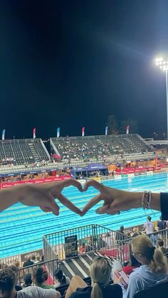 two people making a heart shape with their hands in front of an empty swimming pool