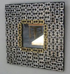 a mirror that is on the side of a wall with some metal squares around it