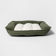 a green dog bed with two white pillows on the bottom and one in the middle