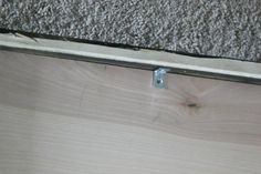 the corner of a wooden floor with a metal strip on it's edge and a piece of wood sticking out from underneath