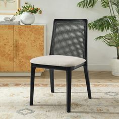 a black and white chair sitting on top of a rug next to a potted plant