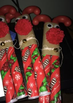 some candy wrapped in red and green wrapping paper with reindeer noses on them, sitting next to each other