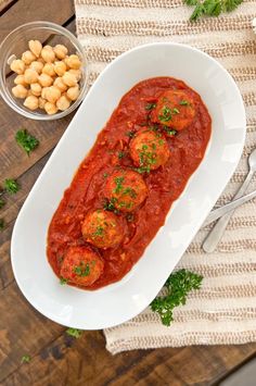 a white plate topped with meatballs covered in sauce and garnished with parsley