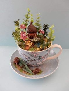 a cup filled with plants sitting on top of a saucer