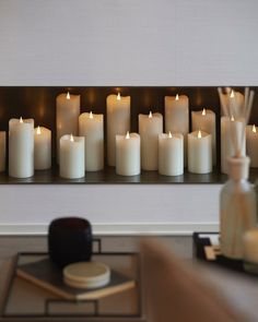 many white candles are lit in front of a mirror on the wall above a coffee table