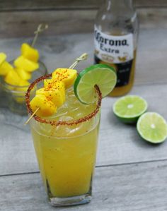 a drink with pineapple and lime garnish in a glass next to some lemon wedges