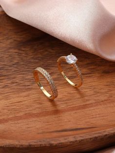 two gold rings sitting on top of a wooden table