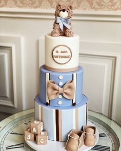 a baby shower cake with a teddy bear on top and shoes around the bottom tier