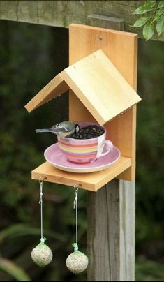 a bird feeder hanging from the side of a wooden fence