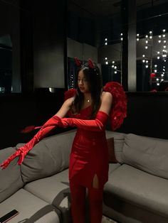 a woman in a red dress is standing near a couch