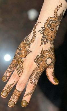 a woman's hand with hennap on it and gold decorations in the middle