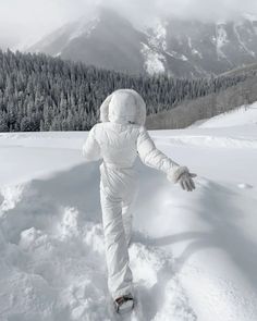 a person in white snowsuit walking through the snow