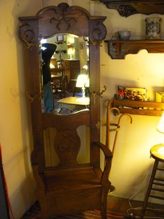 an old wooden armoire with a mirror on the front and shelf above it, next to a lamp