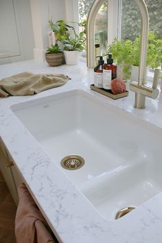 a white sink sitting under a faucet next to a window in a bathroom