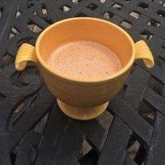 a yellow bowl sitting on top of a wooden table next to a metal grate