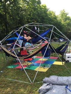 several tents set up in the grass with hammocks