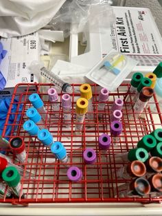 a red wire rack filled with lots of different colored markers and tubes on top of it