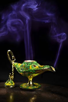 a green and yellow bird shaped container with a chain hanging from it's neck