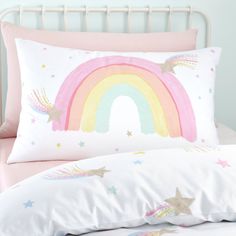 a pink bed with a rainbow pillow on it