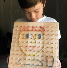 a young boy holding up a wooden board with an electronic circuit on it