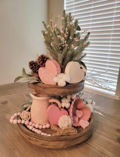 three tiered tray with pink and white decorations on top of wooden flooring next to window