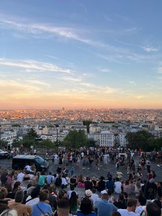 a crowd of people standing on top of a parking lot in front of a city