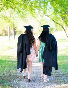 two graduates walking down a path holding hands