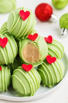 green chocolates with red hearts cut in half on a plate next to christmas ornaments