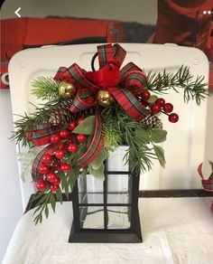 a lantern decorated with holly, berries and pine cones