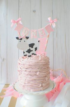 a cake decorated with pink frosting and a cow on top that says'one '