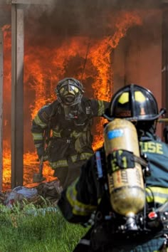 two fire fighters in front of a burning building