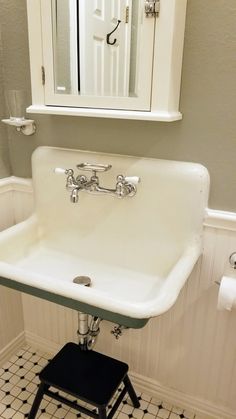 a white sink sitting under a bathroom mirror next to a black and white checkered floor