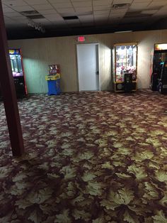 an empty room with two vending machines in the corner and carpeted flooring