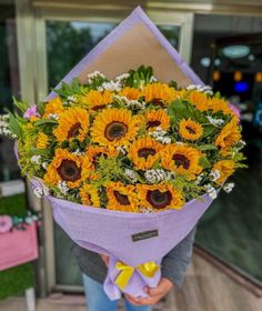 a person holding a bouquet of sunflowers in their hands