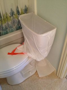 a white toilet sitting in a bathroom next to a bath tub covered in plastic wrap