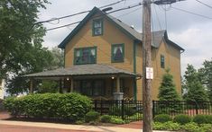 a yellow house with green trim on the front and side of it's roof