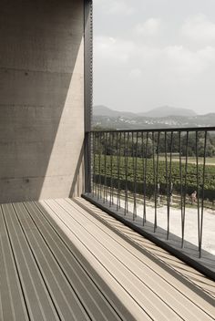 an empty balcony with wooden flooring and metal railings on the side of a building